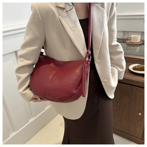 Detail of burgundy PU leather saddle bag with knot strap on a model in a French setting