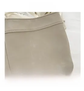 Close-up detail of off-white bucket bag showing grain texture and stitching