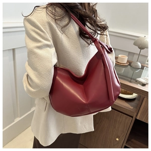 Detail view of burgundy half-moon saddle bag with knot strap and soft matte leather texture
