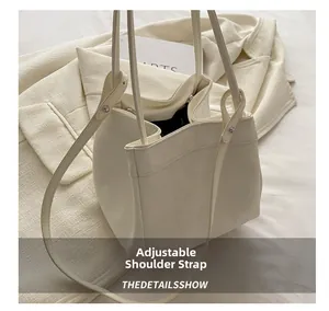 Detail view of the beige bucket bag showing adjustable shoulder strap and leather texture
