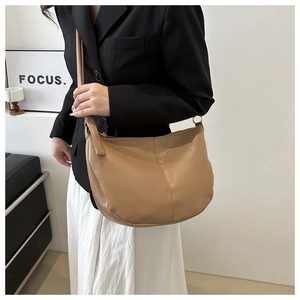 Minimalist tan PU leather half-moon saddle bag for women shown as a stylish shoulder bag