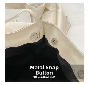 Macro detail of high-quality magnetic snap closure on cream leather bucket bag