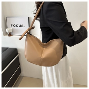 Detail of camel PU leather half-moon shoulder bag featuring a knotted strap design