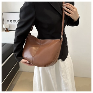 Brown leather hobo saddle bag shown styled with a black blazer and white skirt