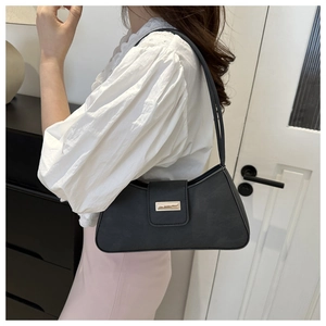 Vintage black leather underarm bag with gold buckle shown on shoulder for classic style