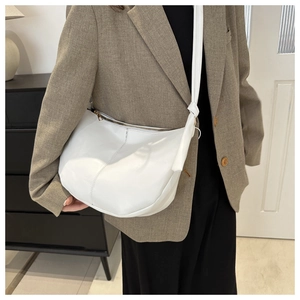 Detail of white PU leather crescent tote bag with knot accent and stitch texture