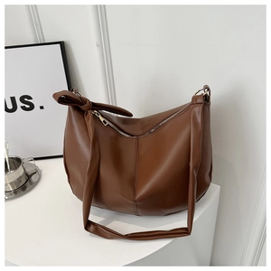 Detail view of smooth brown faux leather hobo bag with a knotted wide shoulder strap
