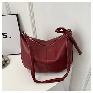 Detail of dark red crescent tote bag featuring knotted strap and silver metal zipper
