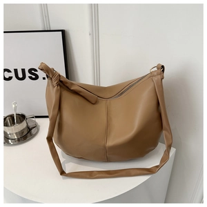 Detail view of brown PU leather crescent tote bag featuring unique shoulder strap knot