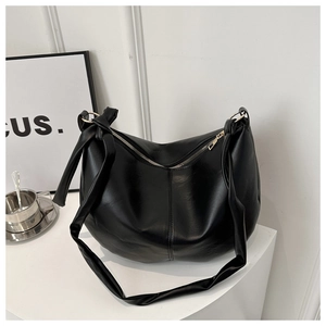 Detail of black PU leather hobo bag with knotted wide strap and light gold hardware