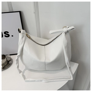 Detail of white hobo tote bag featuring a knotted shoulder strap and gold zipper closure