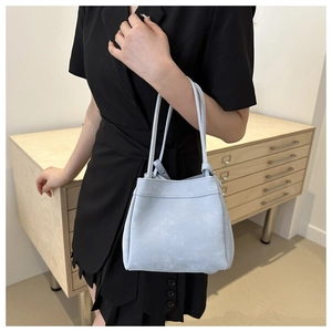 Close-up of light blue leather tote bag with subtle marble texture and thin handles