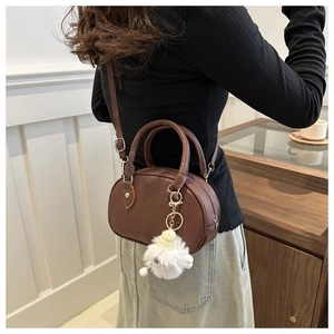 Détail d'un sac à main bowling marron foncé avec un charmant pendentif en peluche