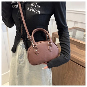 Détail d'un sac bandoulière ovale marron avec bandoulière réglable et zip argenté