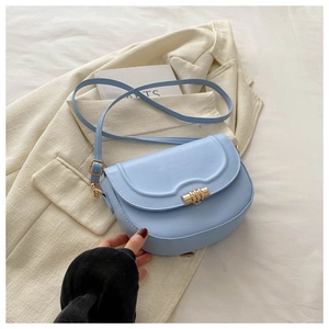 Detail of light blue saddle bag with gold buckle on a stylish cream blazer jacket