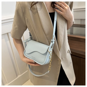 Close-up of light blue crossbody bag with scalloped flap and gold chain strap detail