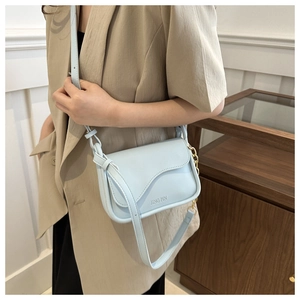 Detail of light blue crossbody bag with wavy flap design and gold chain accents