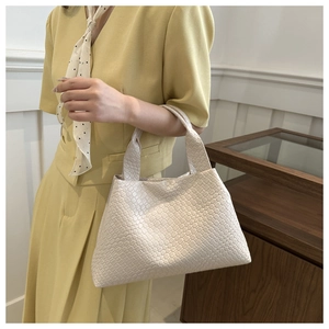 Minimalist beige woven tote bag with large capacity in a stylish professional setting