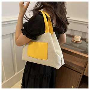 Detail of canvas tote bag featuring contrast yellow pocket and sturdy top handles