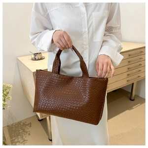 Detail of dark brown woven texture PU leather tote bag with handle in modern setting