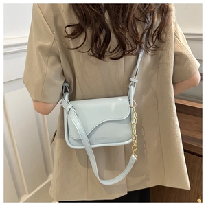 Detail of baby blue crossbody bag featuring unique wave flap and golden chain strap