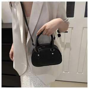 Détail d'un mini sac Boston en cuir noir mat avec finitions argentées et bandoulière