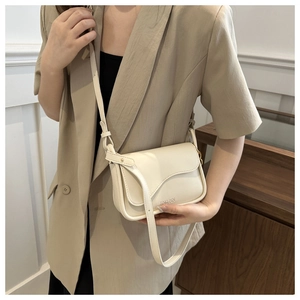 Detail of cream crossbody bag featuring a unique wavy flap edge and gold hardware