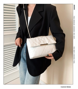 White quilted chain crossbody bag shown on a model wearing a black blazer and jeans