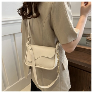 Detail view of cream crossbody bag with gold chain strap and textured leather finish