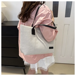 Detail view of large nylon canvas tote bag worn by a model in a modern home setting