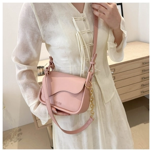 Detailed view of pink synthetic leather crossbody bag with chain strap and curve flap