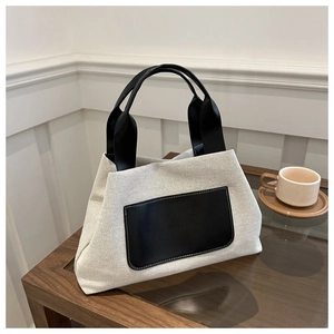 Detail view of canvas bucket bag with black leather pockets and white stitching details