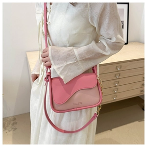 Detail of pink color-block crossbody bag with wavy flap design and gold chain strap
