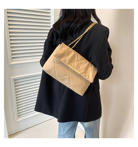 Borsa a tracolla beige trapuntata con catena dorata indossata su un blazer nero
