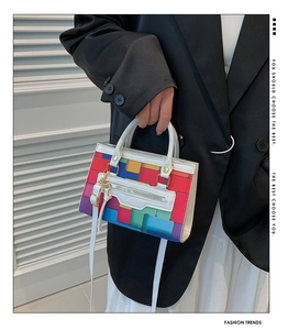Detail of colorful pixel pattern handbag with white handle and decorative front zipper