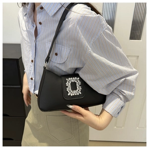 Detail of black underarm bag with sparkling square rhinestone buckle on light blue shirt
