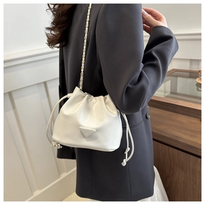 Detail of minimalist bucket bag showing cream leather texture and chain shoulder strap