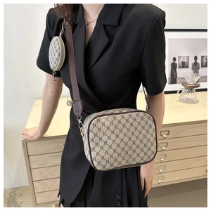 Detail of a brown monogram crossbody bag with a round coin pouch on the strap