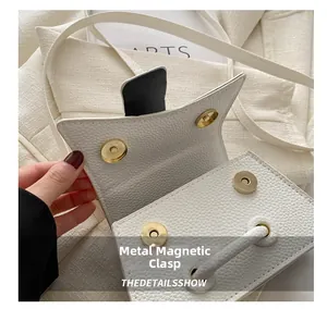 Detail of white lychee leather handbag featuring four golden magnetic metal closures