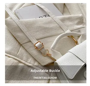 Detail of white pebbled leather shoulder bag with adjustable golden buckle and metal hook