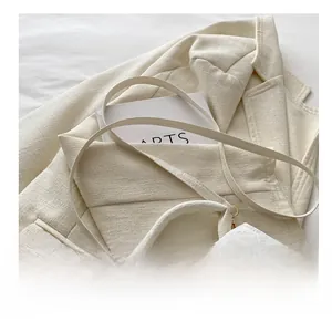 Close-up of the white lychee leather texture and durable shoulder strap hooks on handbag