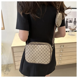 Close-up of a retro monogram crossbody bag with adjustable strap and small round pouch