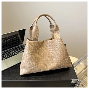 Elegant beige woven texture tote bag with large capacity displayed on a desk