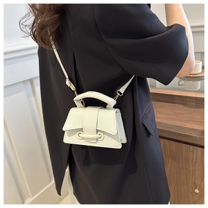 Close-up of a white lychee grain mini handbag worn by a model in a minimal home setting