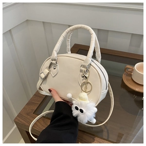 Détail du sac bowling blanc crème avec charme monstre en peluche et texture similicuir