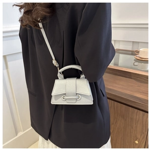 Close-up of a silver mini trapezoid handbag with litchi texture on a model shoulder