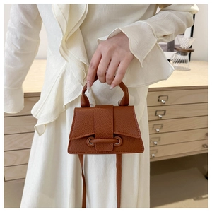 Mini dark brown lychee leather handbag with top handle and strap in home setting