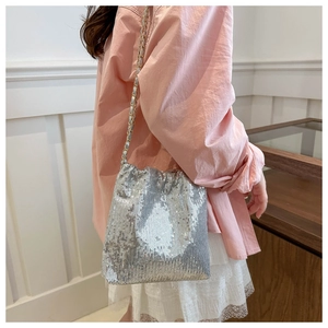 Detail of silver sequin crossbody bag with chain strap worn with a lace skirt