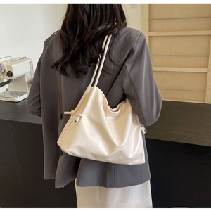 Cream soft PU leather bucket bag with long shoulder straps in a modern cafe setting