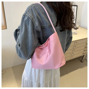Close-up of pink minimalist shoulder bucket bag with embroidery on a soft fabric
